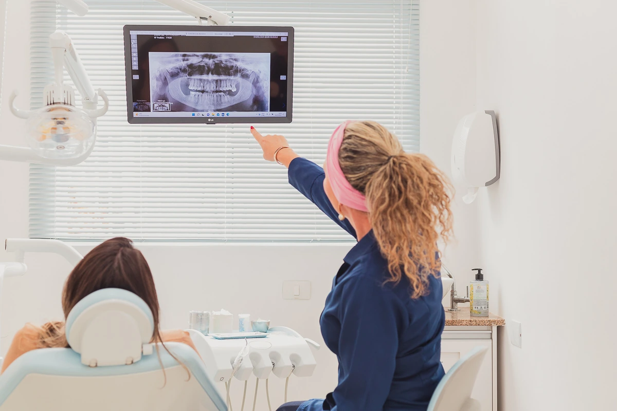 Dentista mostrando uma radiografia panorâmica a uma paciente no consultório